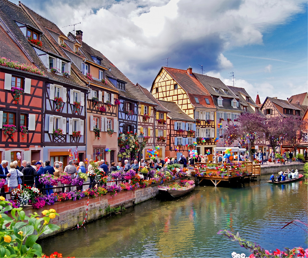 Canal animé de la Petite Venise à Colmar bordé de maisons à colombages fleuries